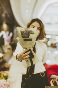 woman holding a bouquet of flowers outside flower shop
